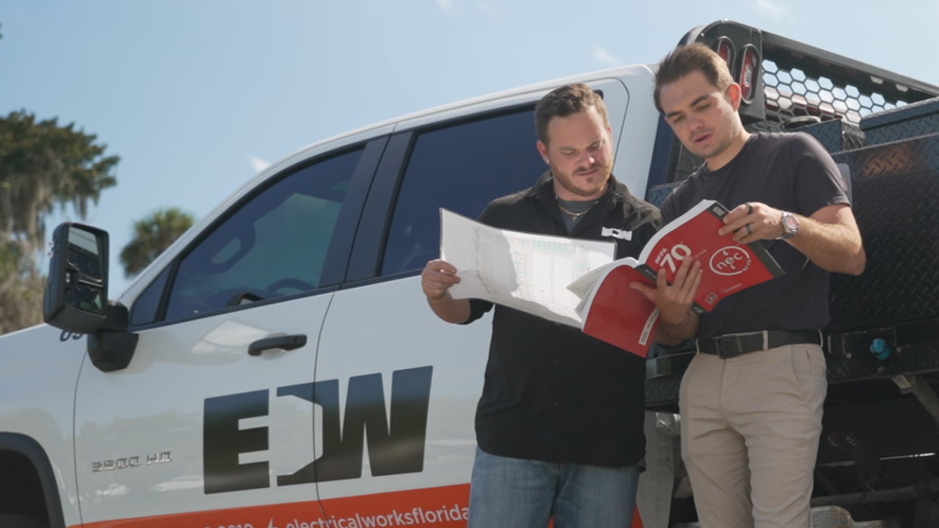2 EW employees examining GMI compliance near Truck